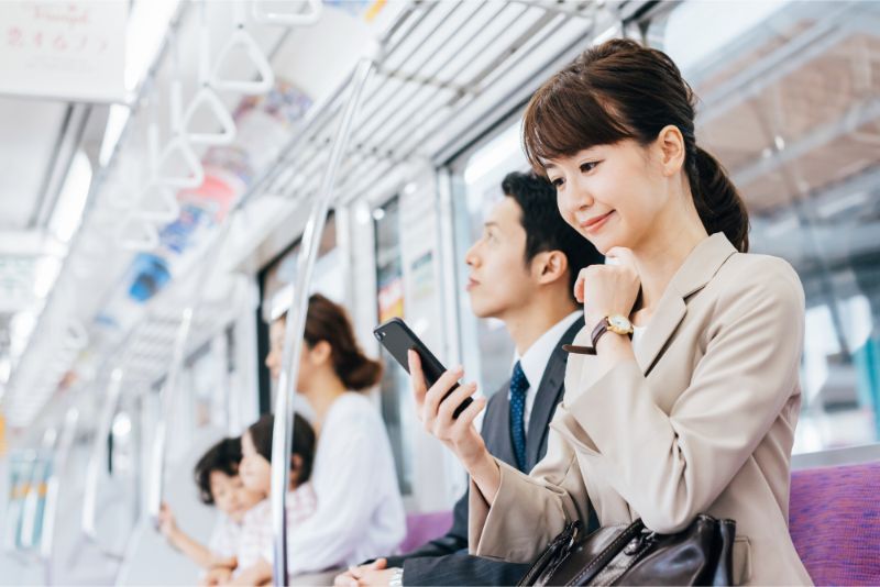 電車の中でスマートフォンを使用する女性
